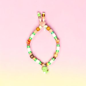 Collier dinosaure pour chien Dino Gozo en perles céramiques EM, création artisanale PEPS4PETS®, avec perles vert tendre, beige, bois naturel et orange, perles phosphorescentes entourant les perles céramiques EM, paracorde phosphorescente de 4 mm, pendentif dinosaure, fabriqué à la main à Bayonne.